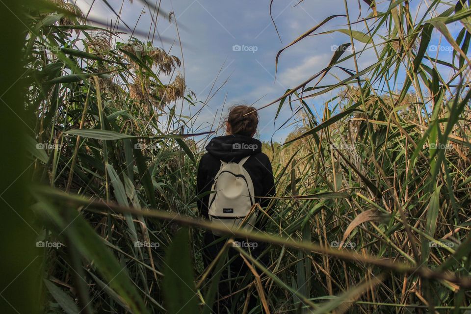 The girl walks through the thickets in autumn.