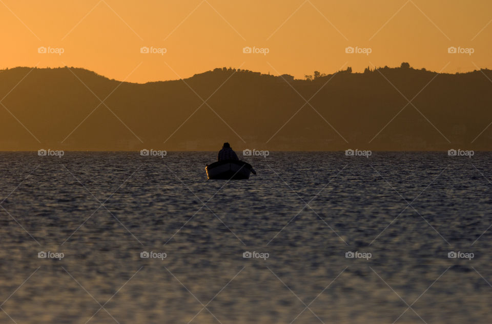 person in boat silhouette in setting sun