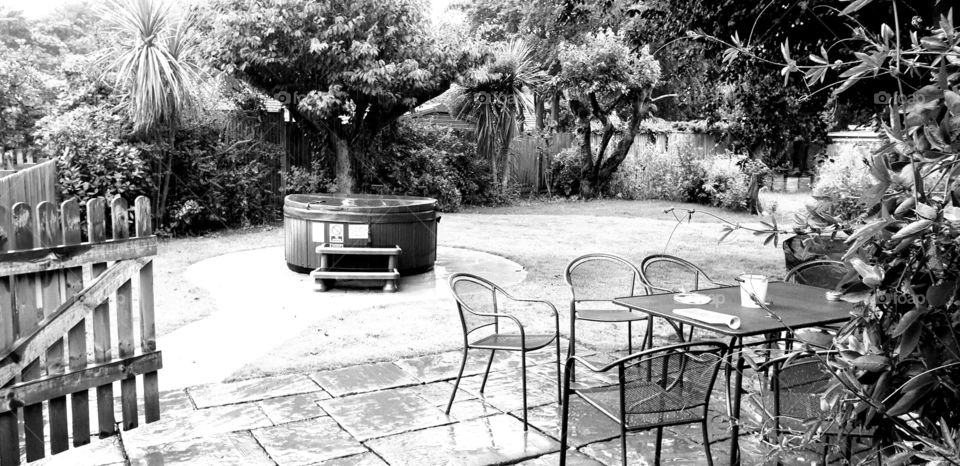 A photo taken through a b/w lens of a outside area with a hottub and chairs