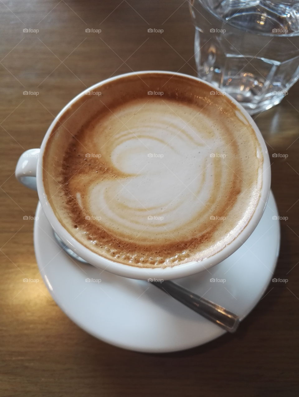 cappuccino with heart shaped design and water on the table