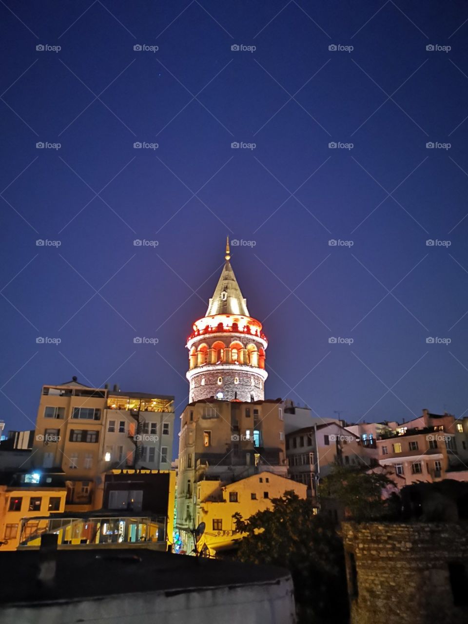 Red and white iluminated the old Galata tower evening view from the terrace of other house.