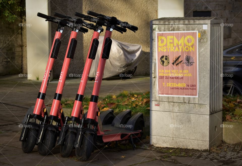 four red scooters in one line and a poster for a demonstration