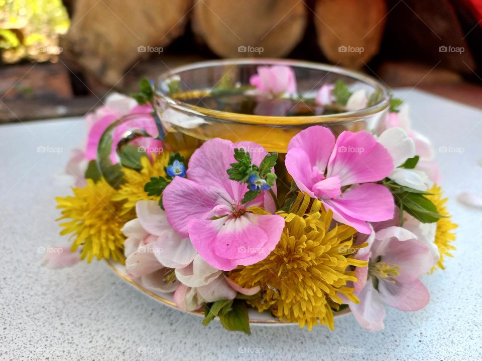 a glass of tea with blooming flowers.