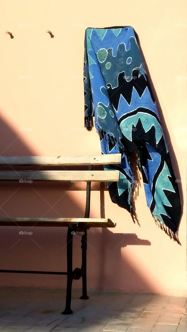 Blue serape blowing in the wind above an antique park bench