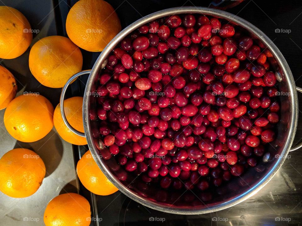 Cranberries and oranges. Thanksgiving harvest. Reds and oranges. cooking cranberries in pot in stove. Making cranberries. Making cranberry juice. Red and Orange color palette.