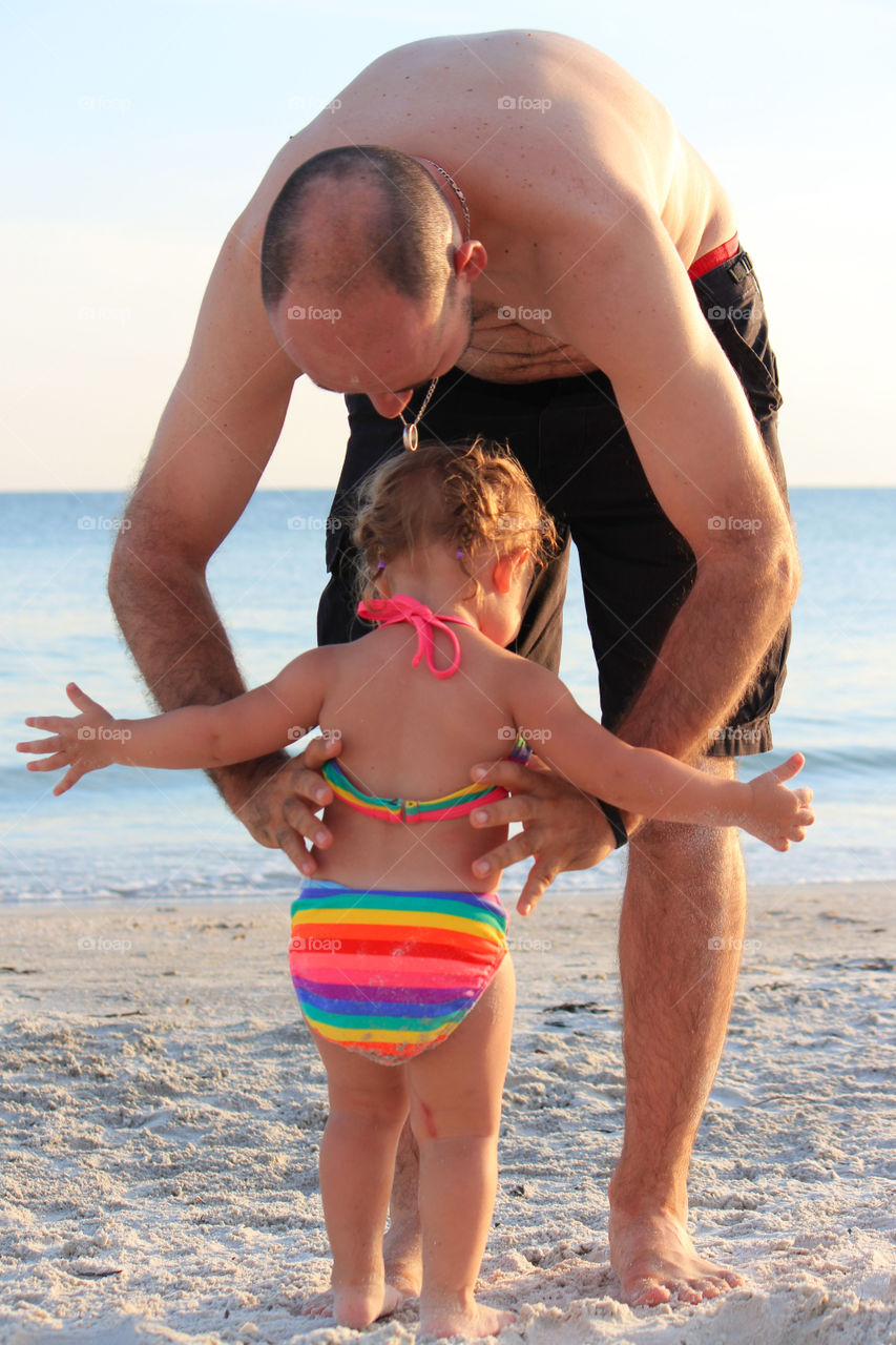 Father playing with his daughter on sandy beach