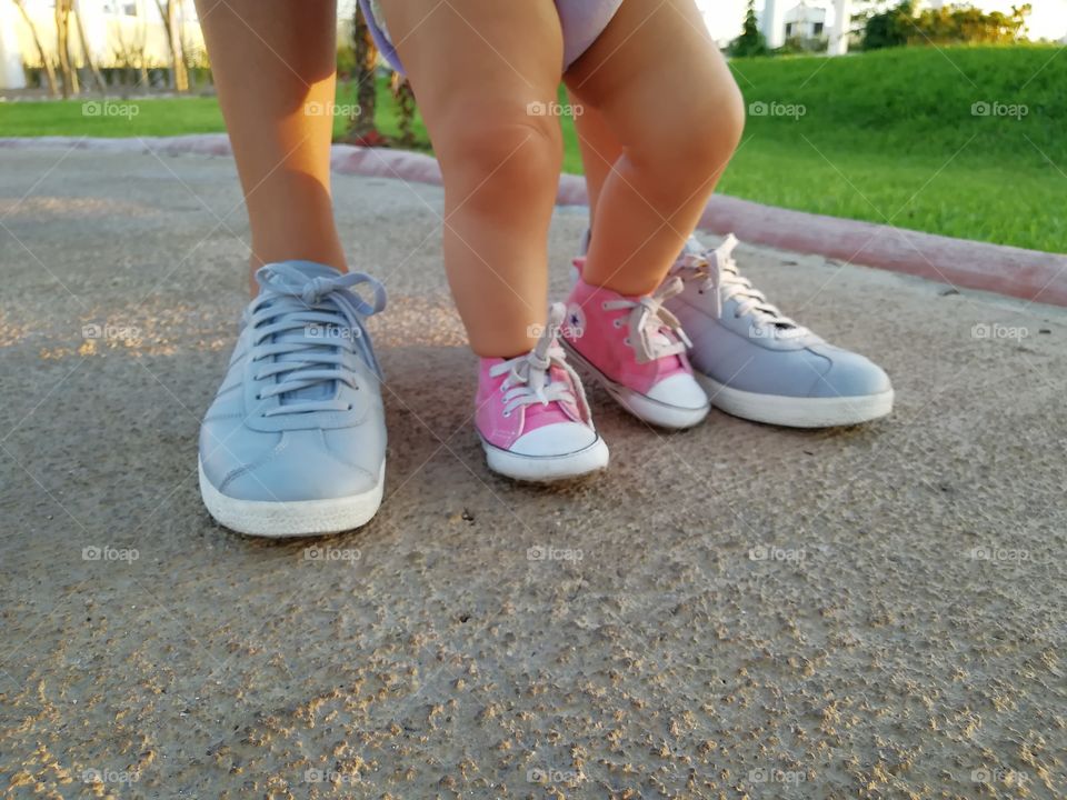 young mother and daughter walking. Closeup to their sneakers.