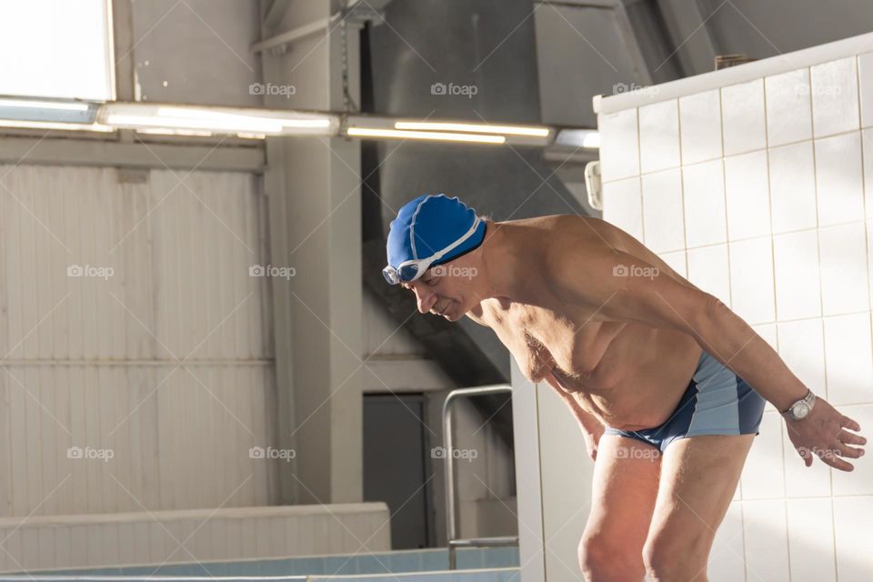 A happy, elderly man is relaxing on vacation in the pool, playing sports and leading an active and healthy lifestyle.