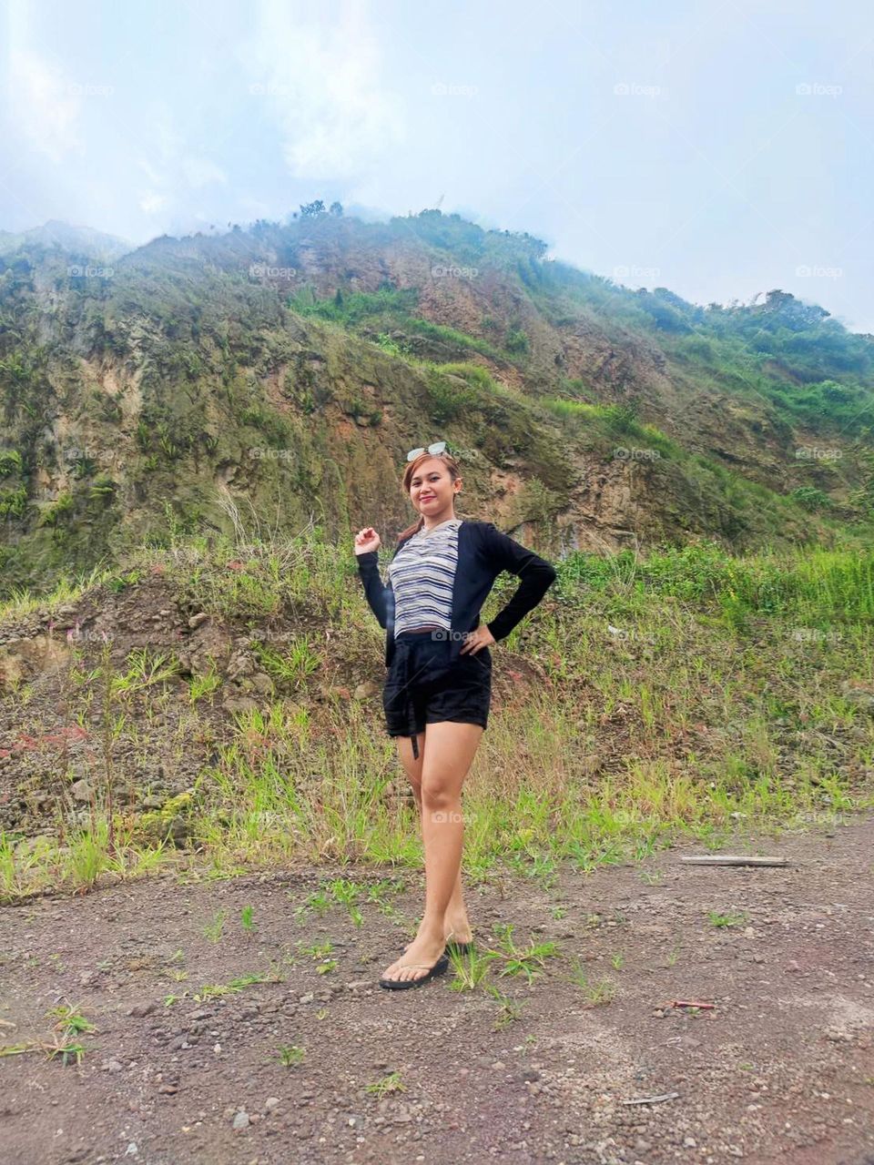 Portrait of young woman standing facing the camera on a beautiful hill