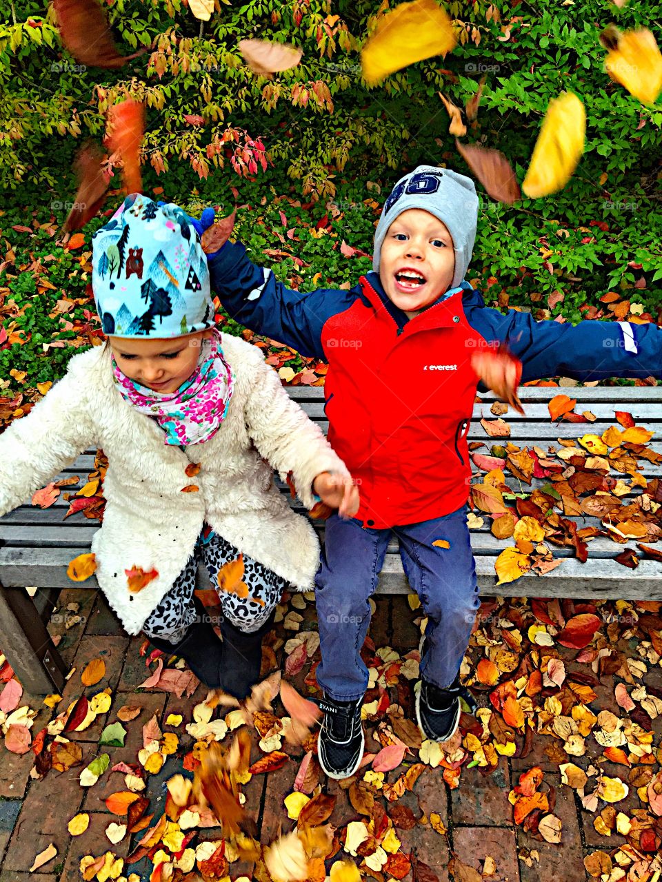 High angle view of happy brother and sister sitting on bench