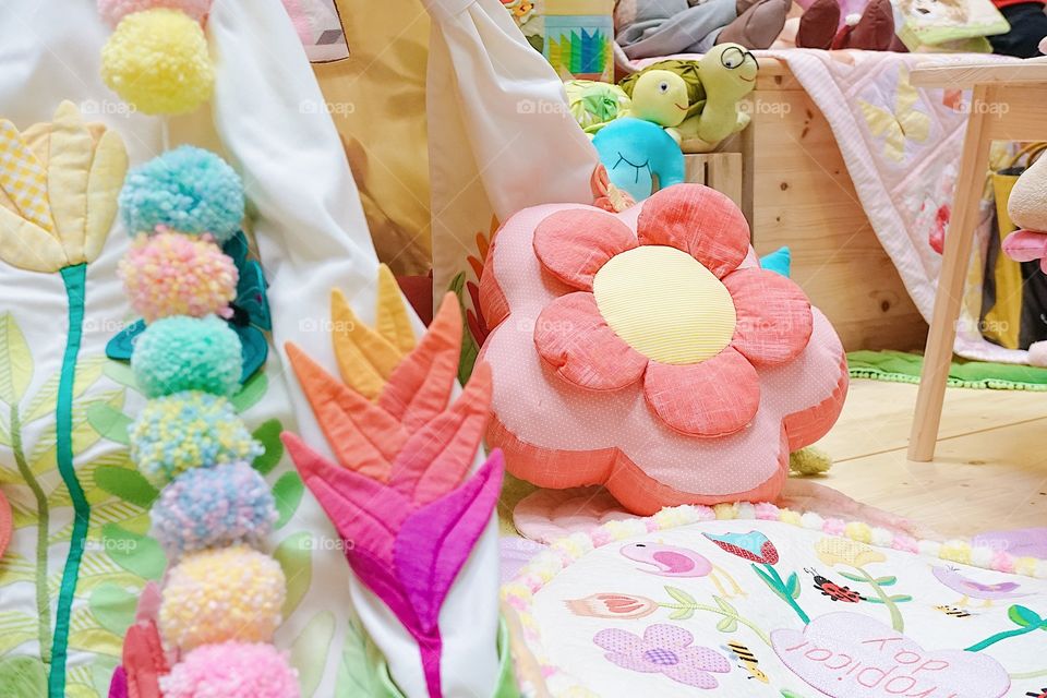 Details of a playroom for children with colorful decorations in spring concept and teepee tent. Selective focus on the pink flower pillow.