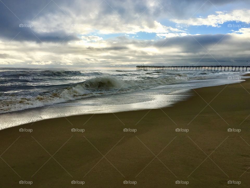 Crashing waves at sunrise near the pier