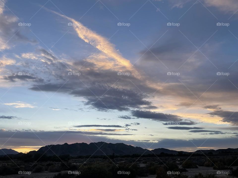 A photo of a pink sunset with mountains and clouds. 