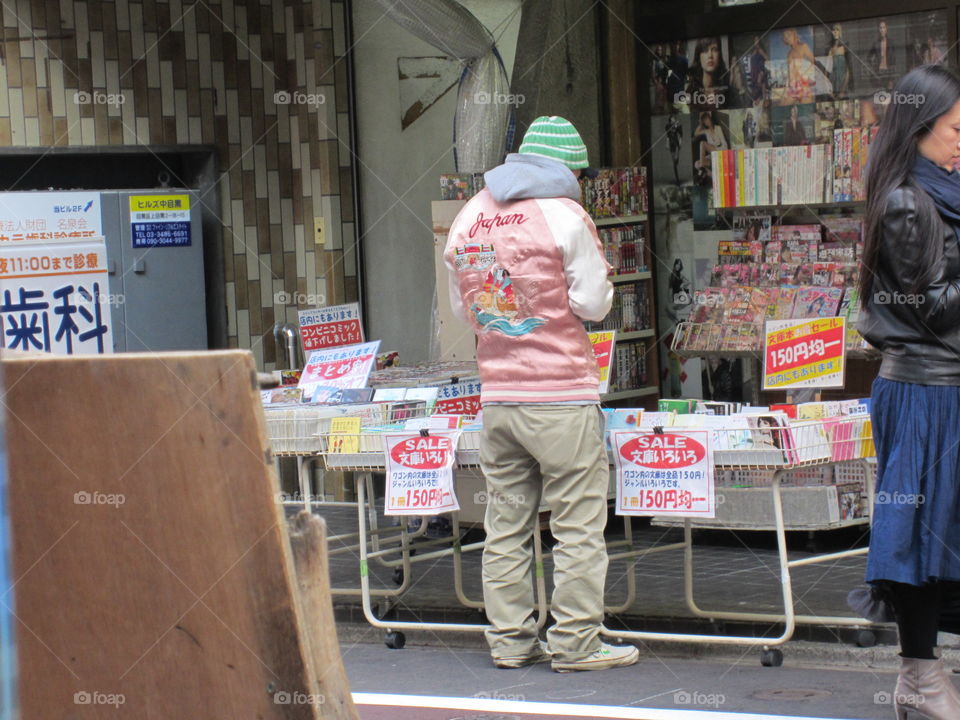 Nakameguro, Tokyo, Japan. Cool Japanese Man checking ouy Magazines in a Pink Satin Jacket