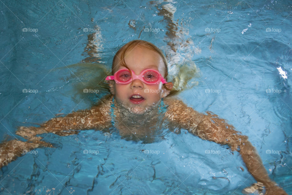 Young girl is swimming in a pool at a hotel.