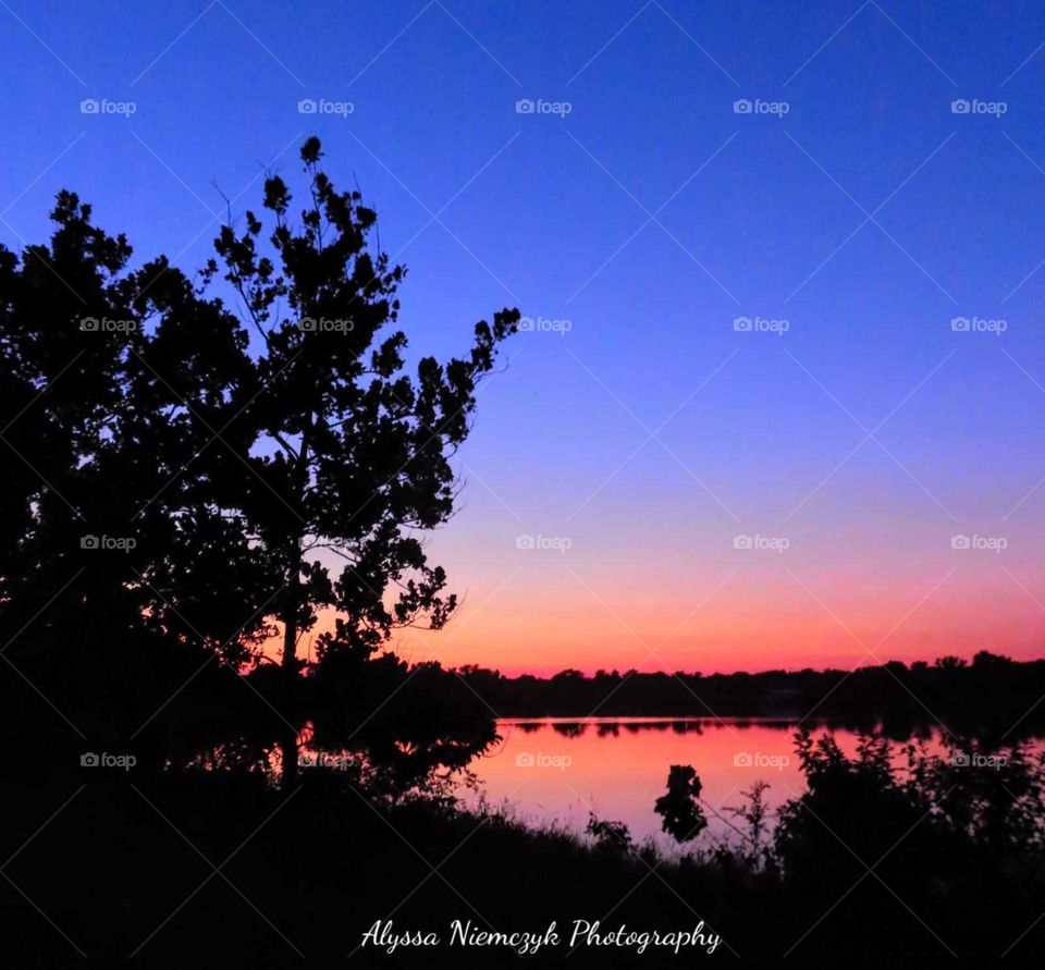 Stunningly colorful sunset along the pond. Crystal clear waters reflect the sky above.