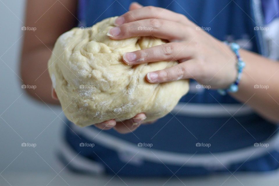 Child's hands are holding bread dough