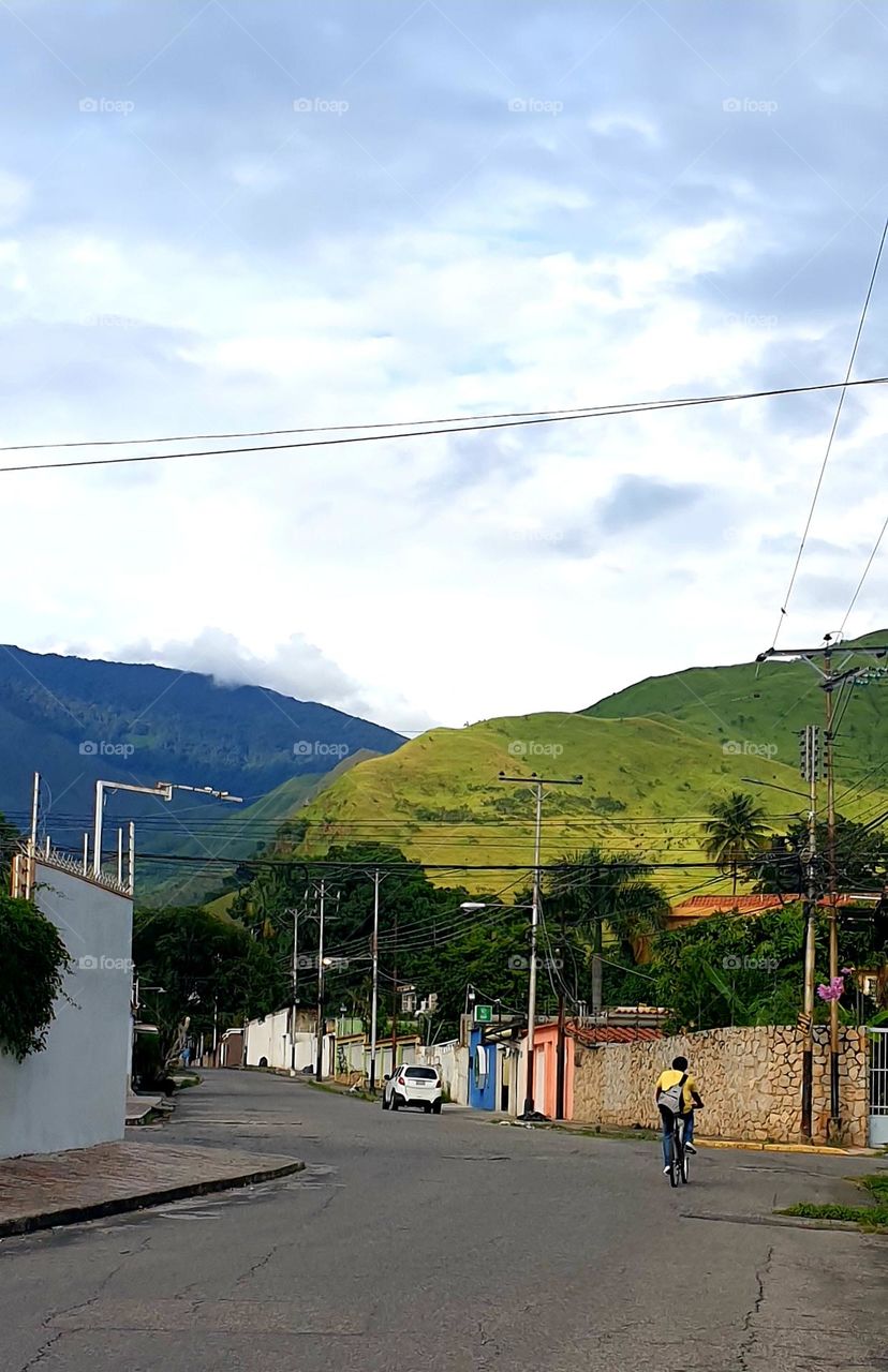 By bicycle taking a ride through the streets seeing the beautiful landscape with green mountains and wonderful sky