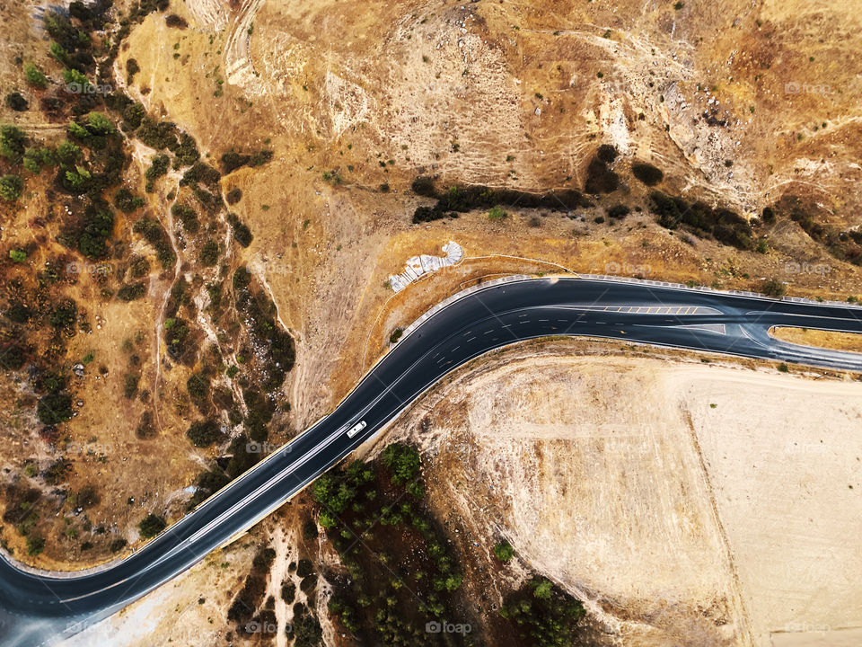 Aerial view of a tiny car moving by the countryside road 