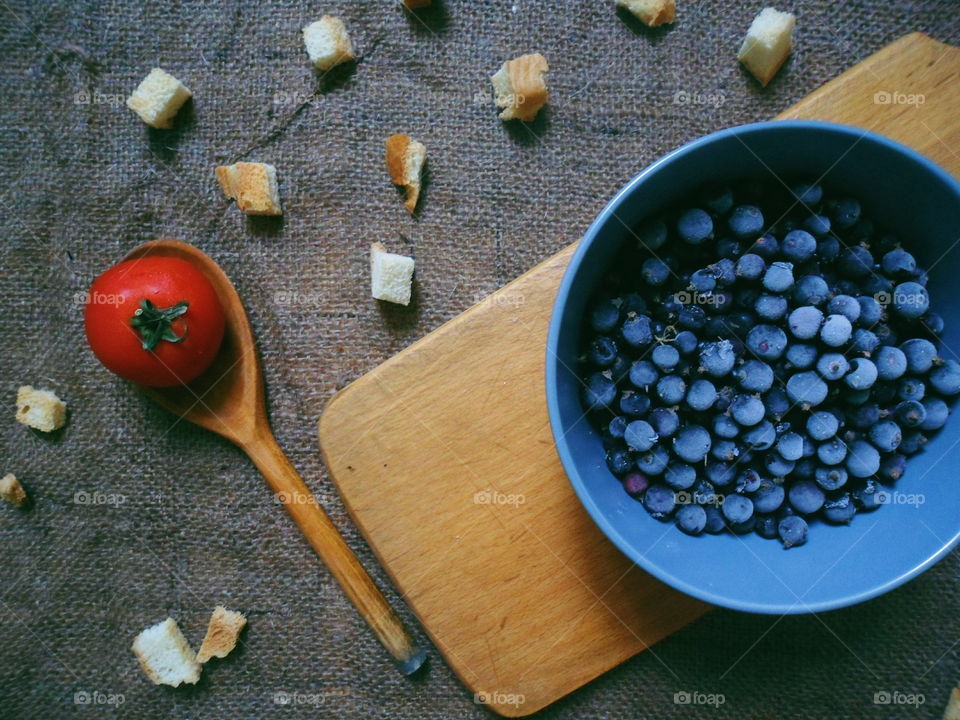 frozen currant, tomato and a wooden spoon on a table