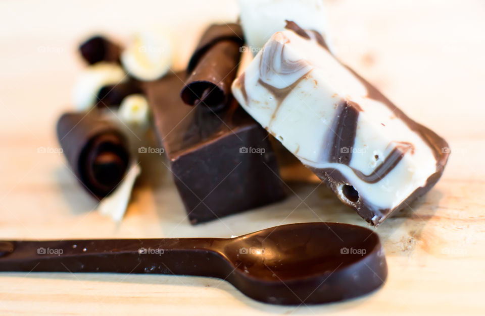 Spoon made of chocolate on wood table in front of chocolate fudge conceptual baking and making gourmet chocolate treats background 