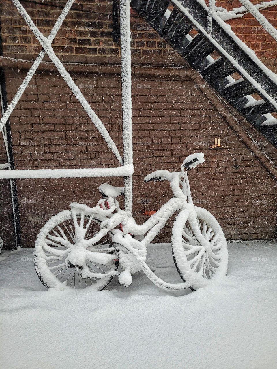 Lonely bicycle standing outside in city street in snowfall.  Winter landscape