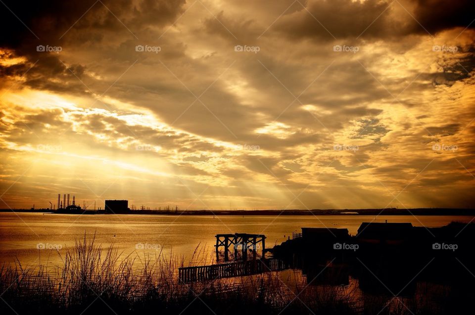 Shafts of light break through the clouds at sunset in a coastal