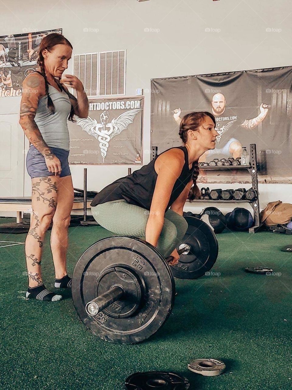 A girl doing deadlifts with a trainer 