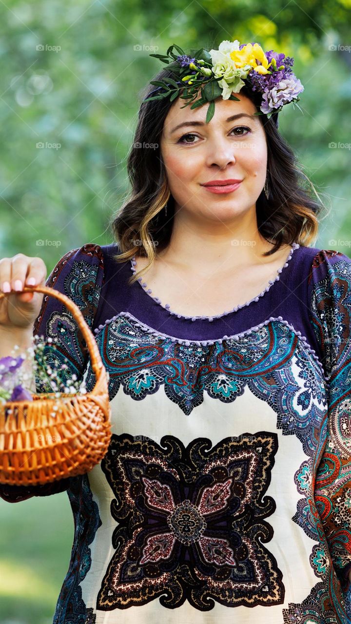 A beautiful woman with a wreath on her head and a basket in her hand.