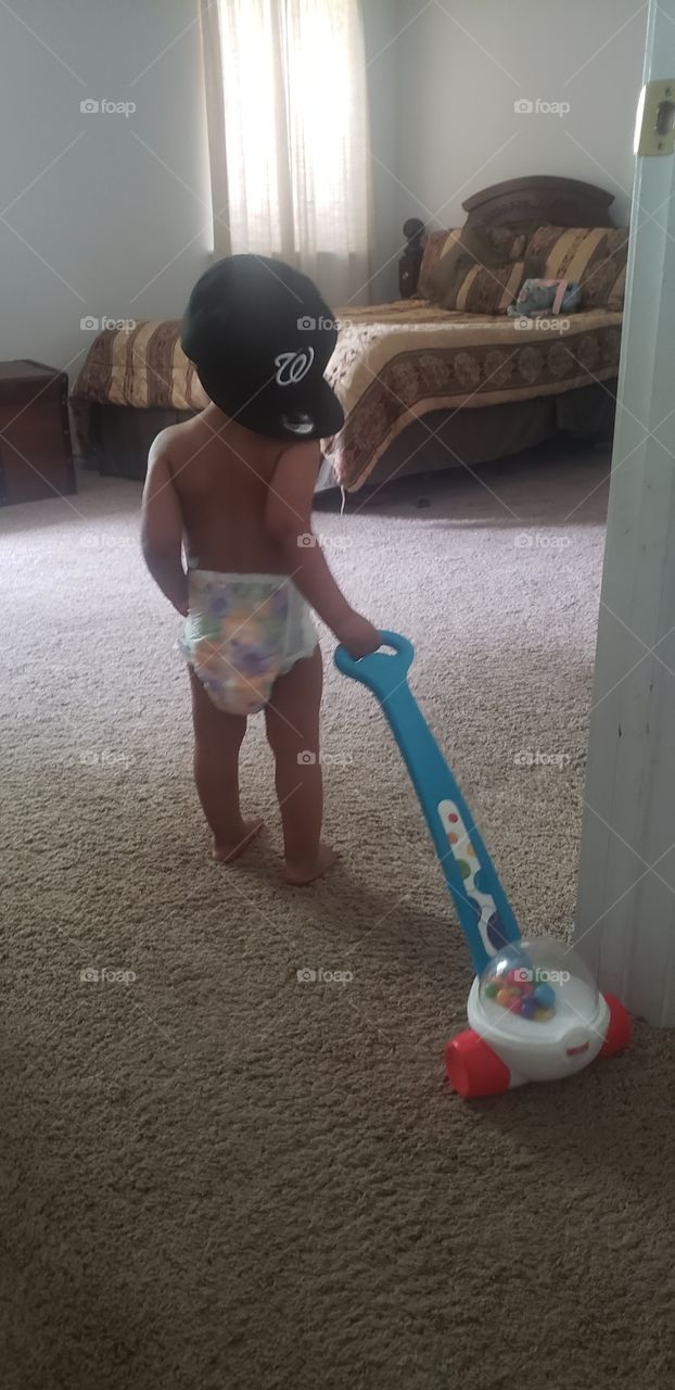 Adorable moment captured of my baby in his dad's hat, dragging around his favorite toy.