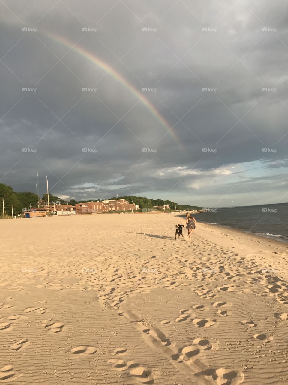 Dog and owner running into the rainbow  on Lake Michigan 