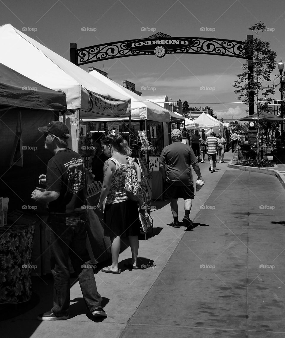 A crowd of people viewing sellers wares at a street fair in Redmond in Central Oregon on a sunny summer day. 