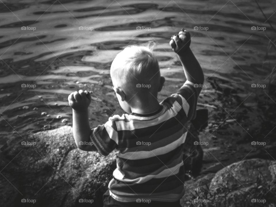 boy throwing rocks in the water