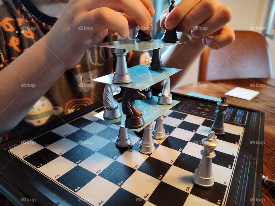 A boy building towers with chess pieces and visit cards
