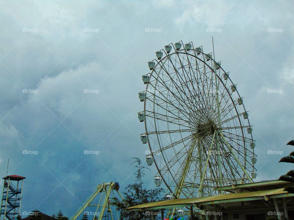 a ferris wheel with the cloudy sky above