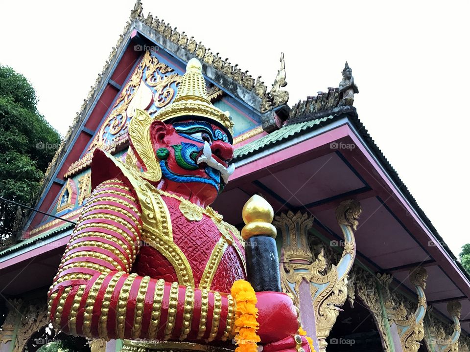 The red demon statue stand a front of buddha temple with isolated white background