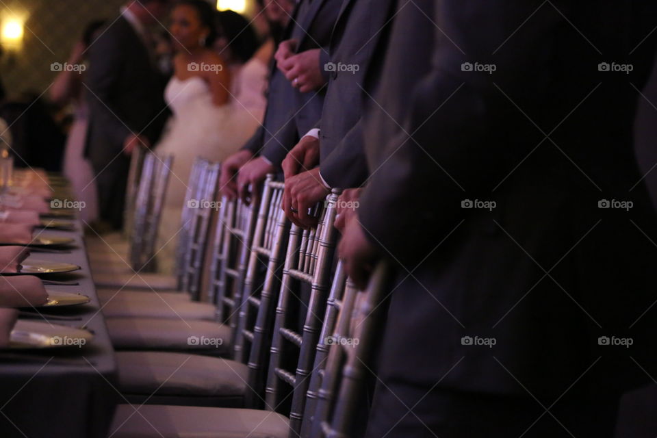 Gentleman's hand. Low shot of groomsmen standing as the bride and groom enter the reception