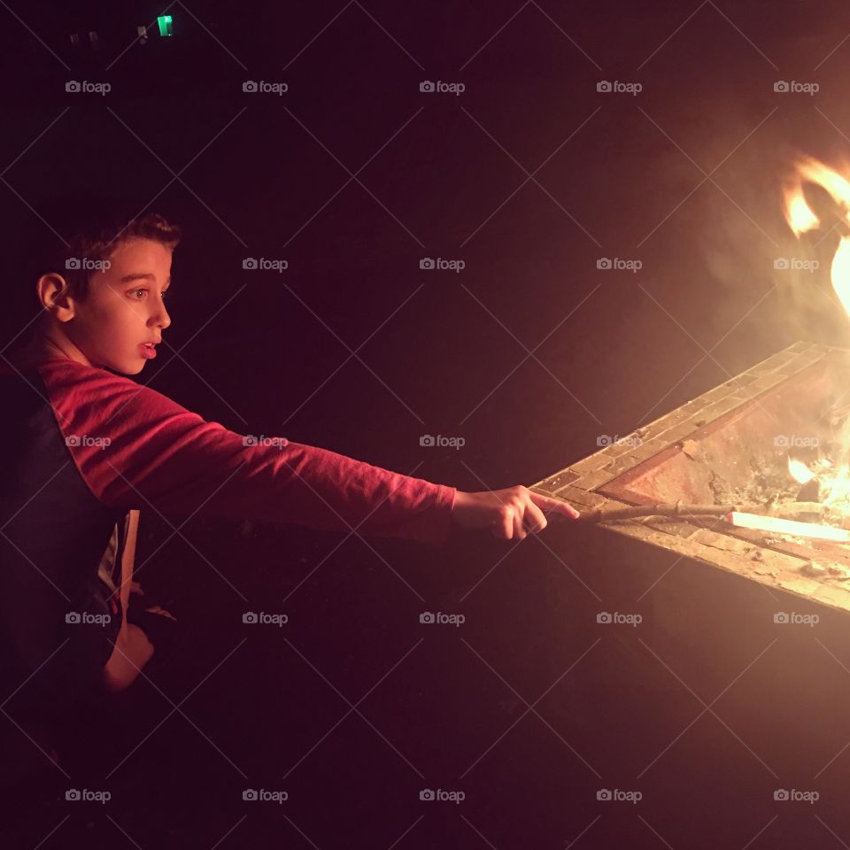 Little boy making fire in a fire pit