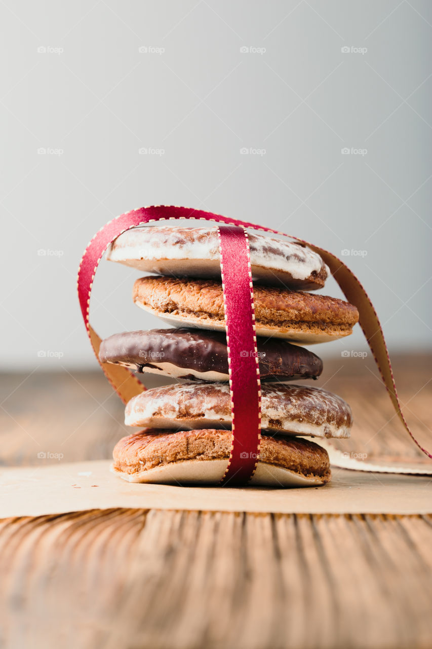 A few gingerbread cookies wrapped in ribbon on wooden table. Plain background. Portrait orientation