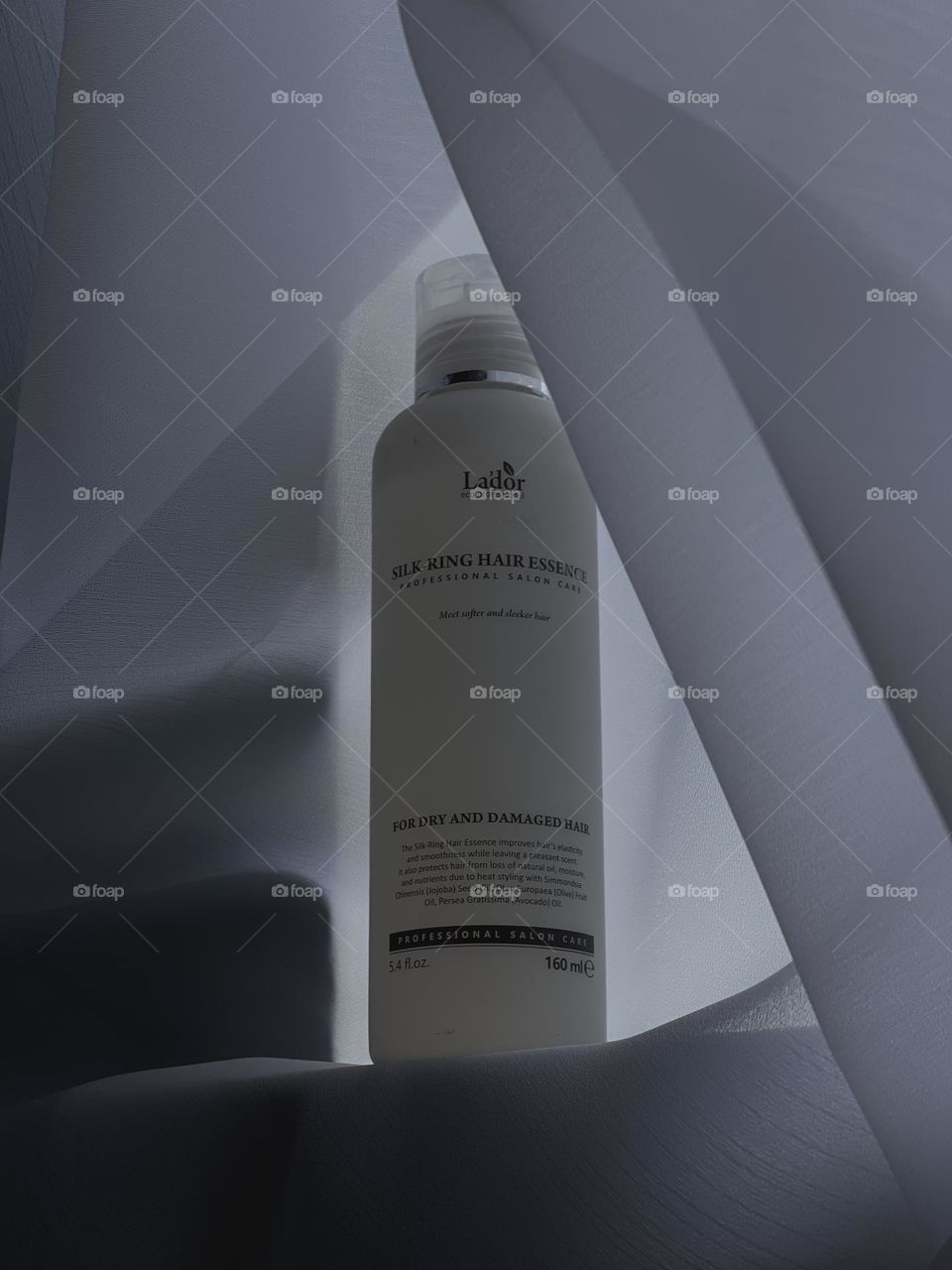 
In the photo, a sleek, minimalist hair product bottle is featured against a clean background. The label on the bottle is simple yet elegant, showcasing the name of the product and its key ingredients.