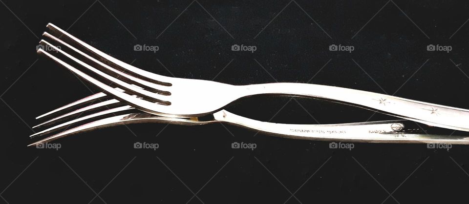 Close up two forks piled isolated on black background. fork made from stainless steel