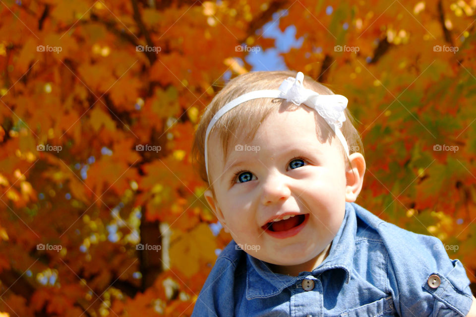 Cute baby girl smiling in front autumn tree