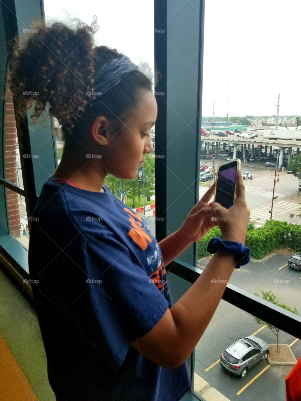 Girl taking pictures outside window.