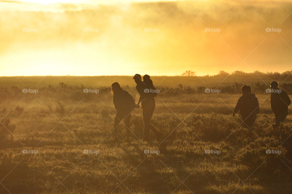 Family heading home in golden field after watching sunrise