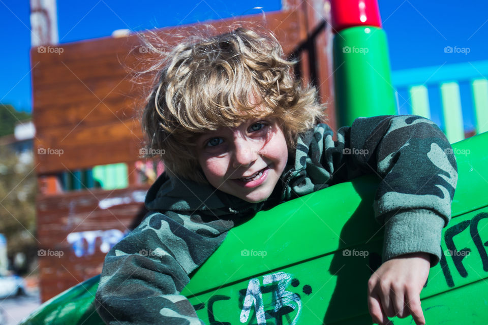 blond boy in the sun on a green slide