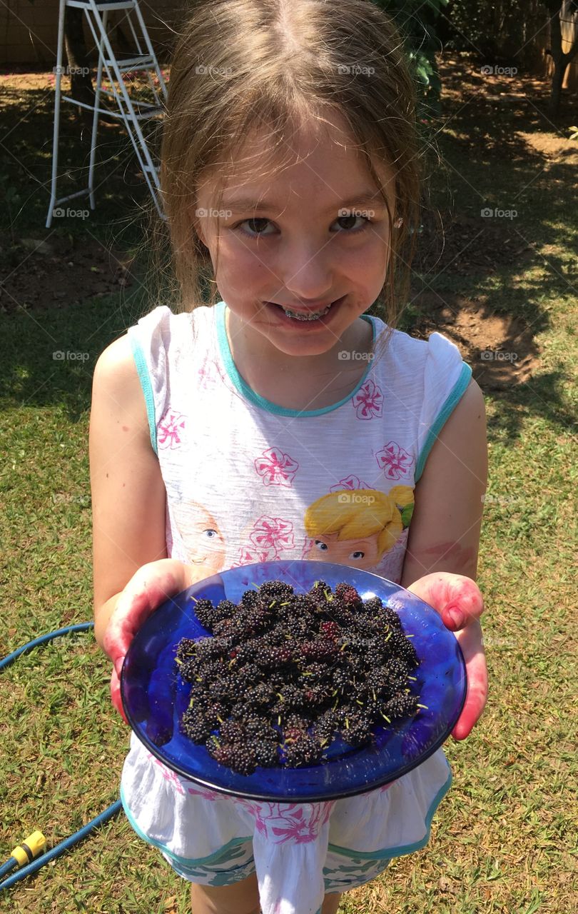 Smiling girl holding plate of blackberries