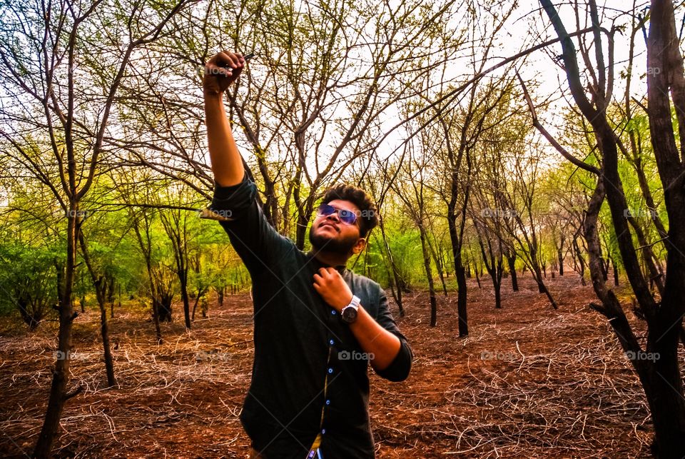 Guy taking selfi using mobile camera  in forest 