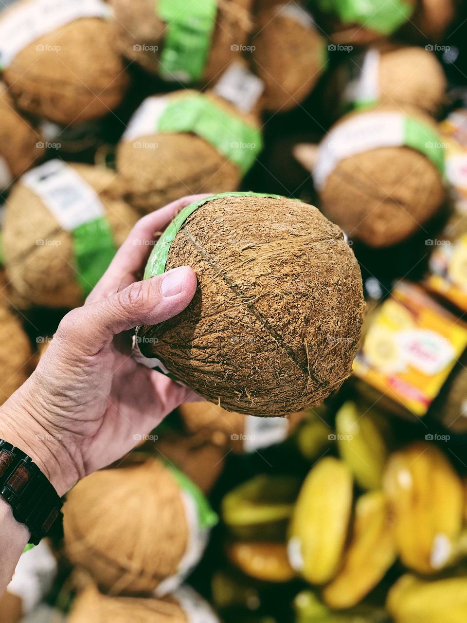 Woman shops for coconuts, shopping in the grocery store, finding good coconuts, shopping in the produce section 