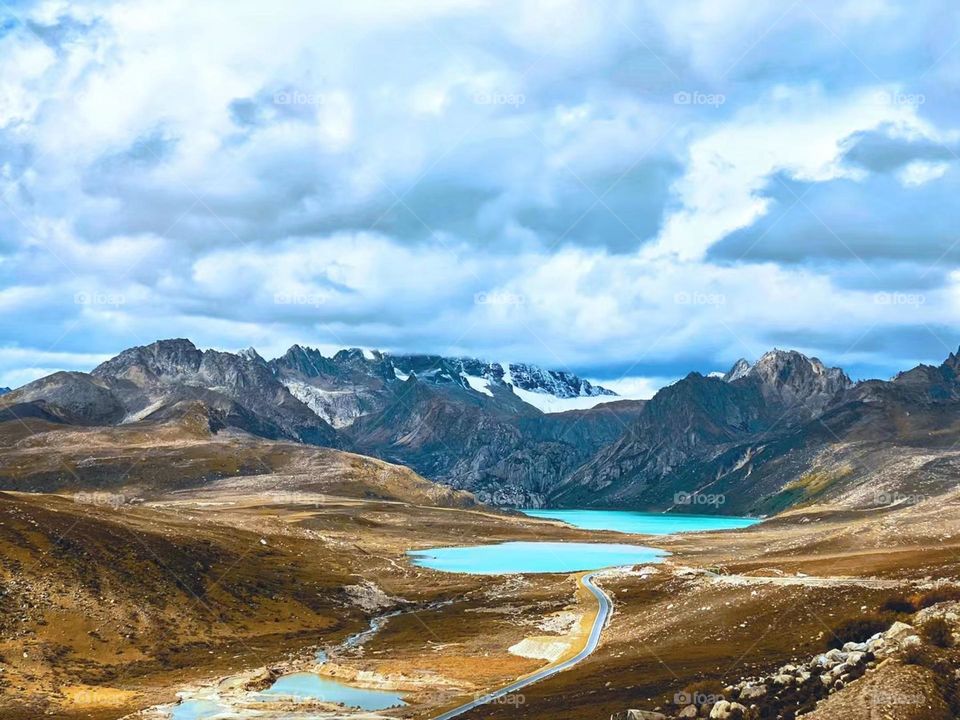 It was taken on the national road 318 in Tibet,China.A turquoise blue gemstone inlays in the mountains.