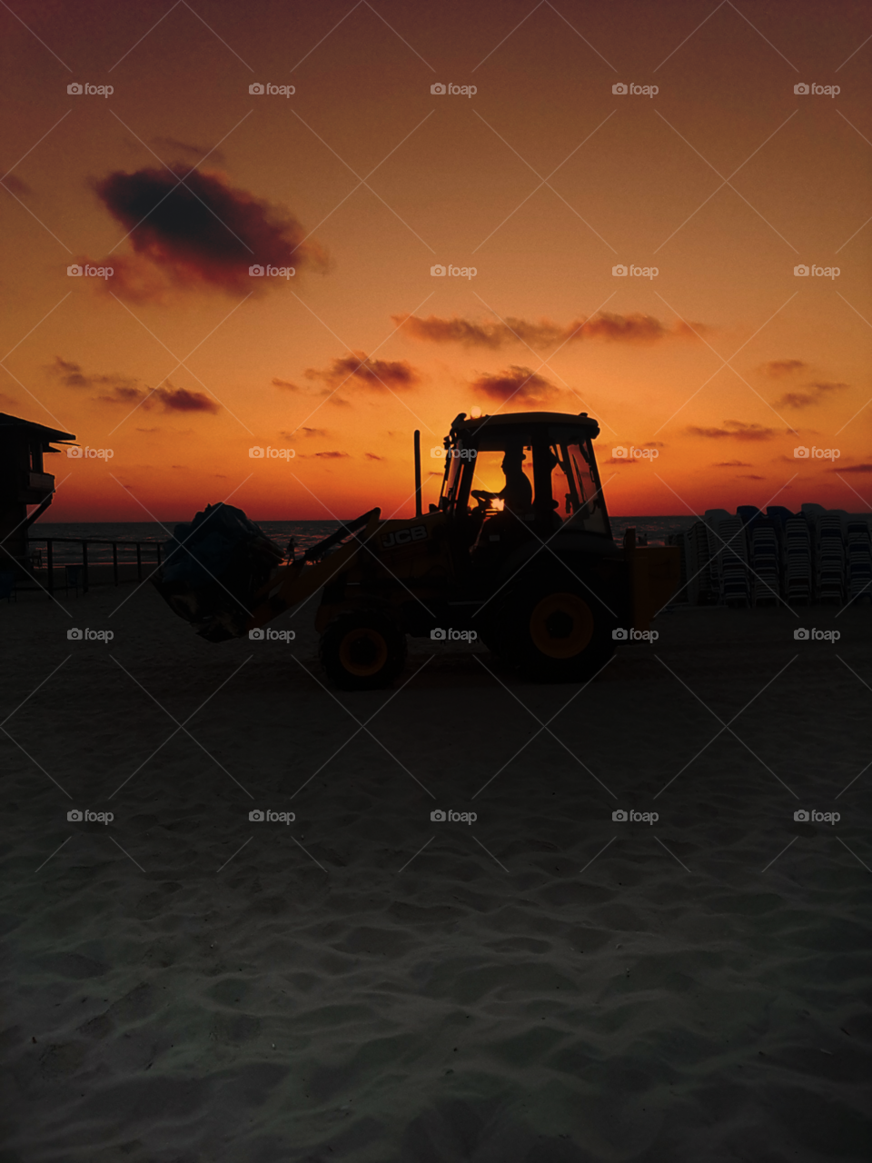 tractor in the sunset cleaning the beach